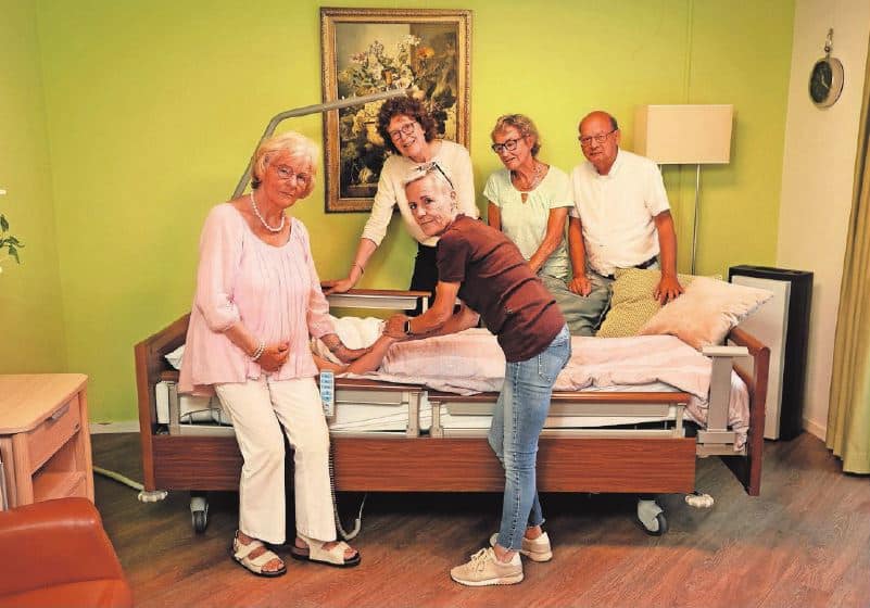 Vrijwilligers VPTZ-NWN staan om het bed van een client.